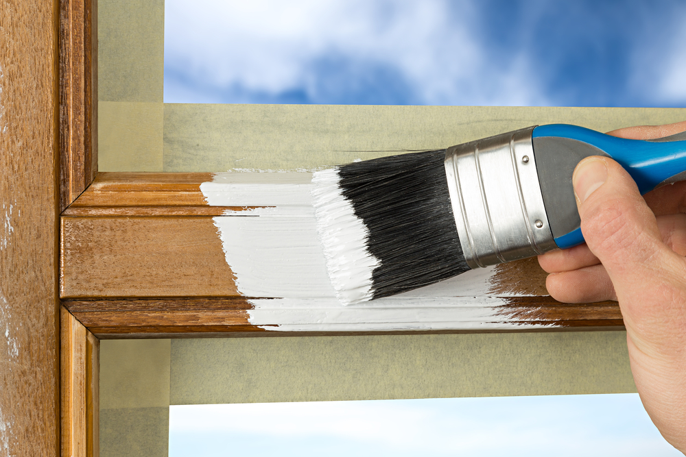 Image of a hand applying primer over a wood frame